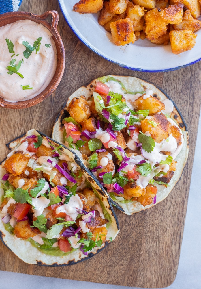 Potato Tacos with Spicy Ranch on a cutting board with toppings