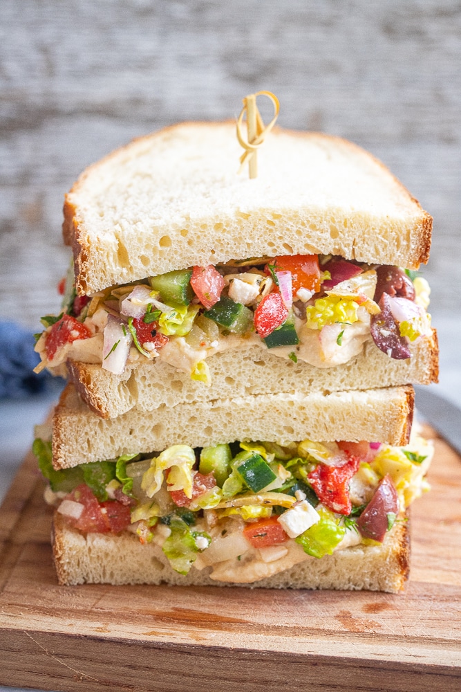 Greek salad sandwiches with hummus on a cutting board