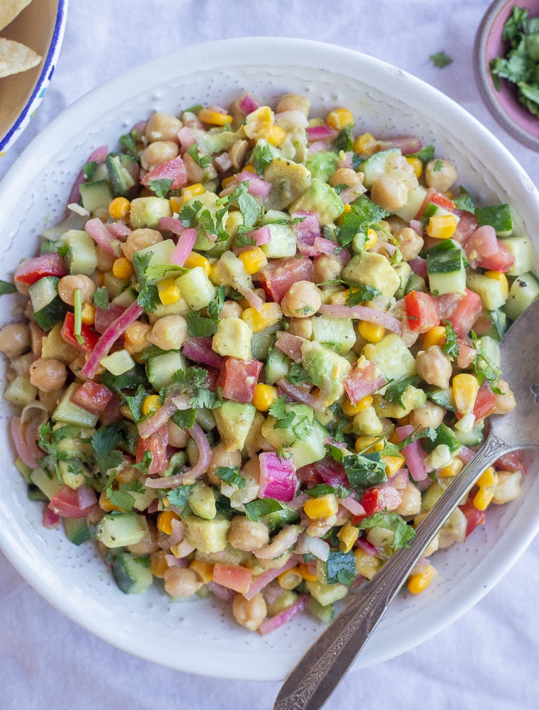 Pickled onion and avocado salad with cucumber in a serving bowl with a spoon