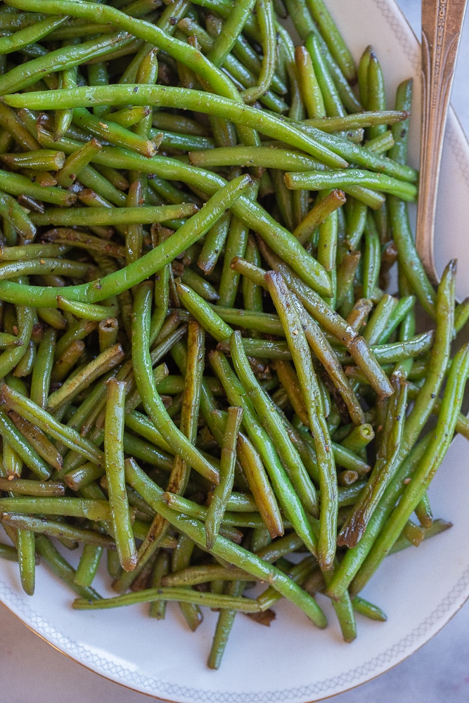 green bean side dish on a platter with a serving spoon