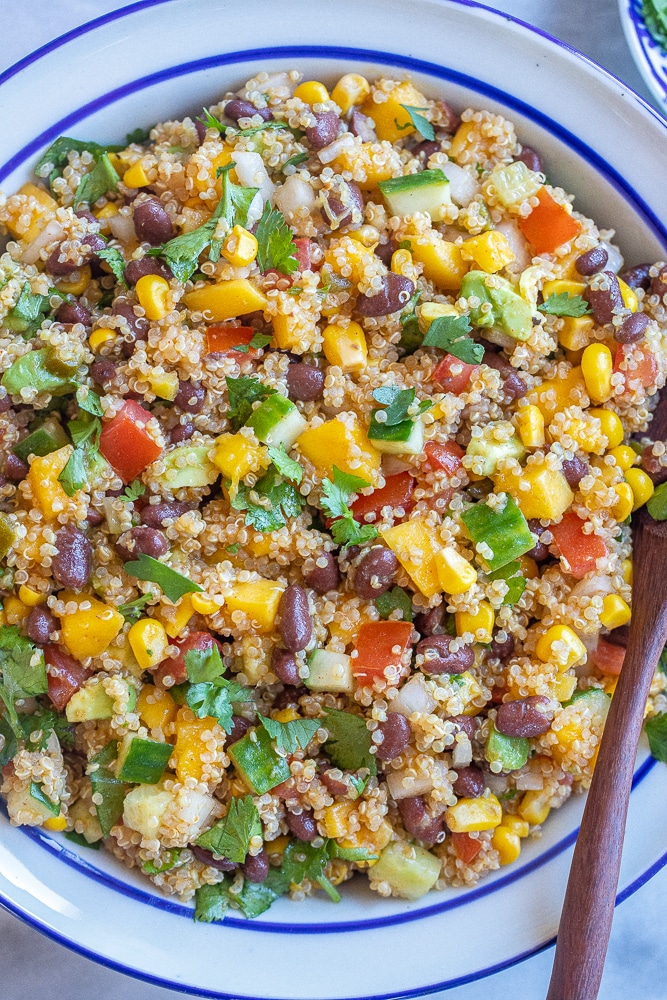 a large bowl of mango black bean quinoa salad with a serving spoon