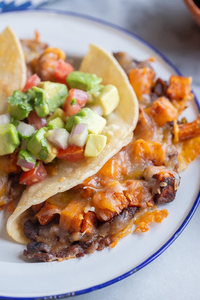 close up of a roasted sweet potato and black bean taco with guacamole