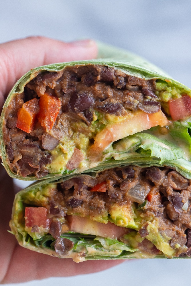close up of a vegan black bean wrap being held by a hand