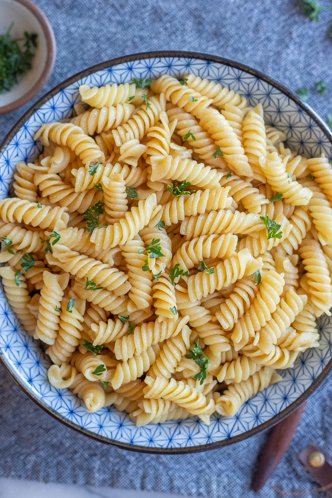 kid's favorite butter noodles in a bowl with a parsley garnish