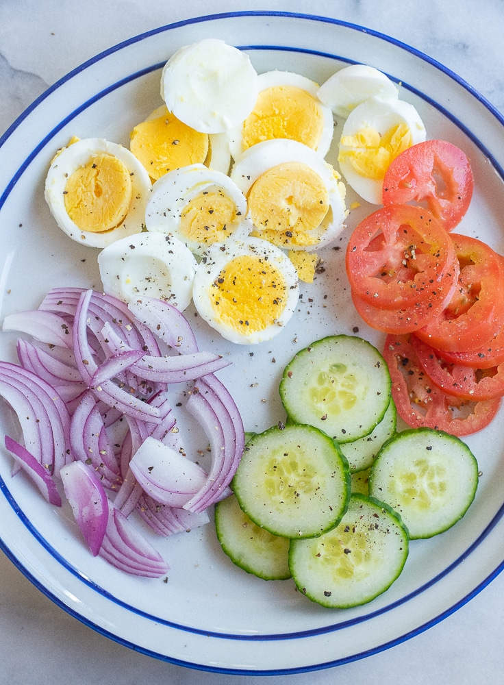 a plate of hard boiled eggs and sliced vegetables for the pitas