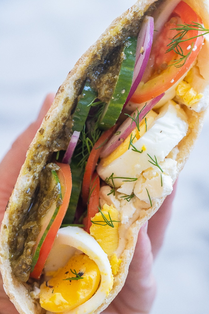 a hand holding a vegetarian breakfast pita 