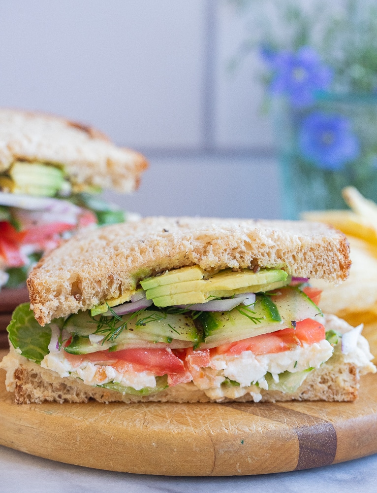 veggie sandwich with hummus and feta cheese on a cutting board