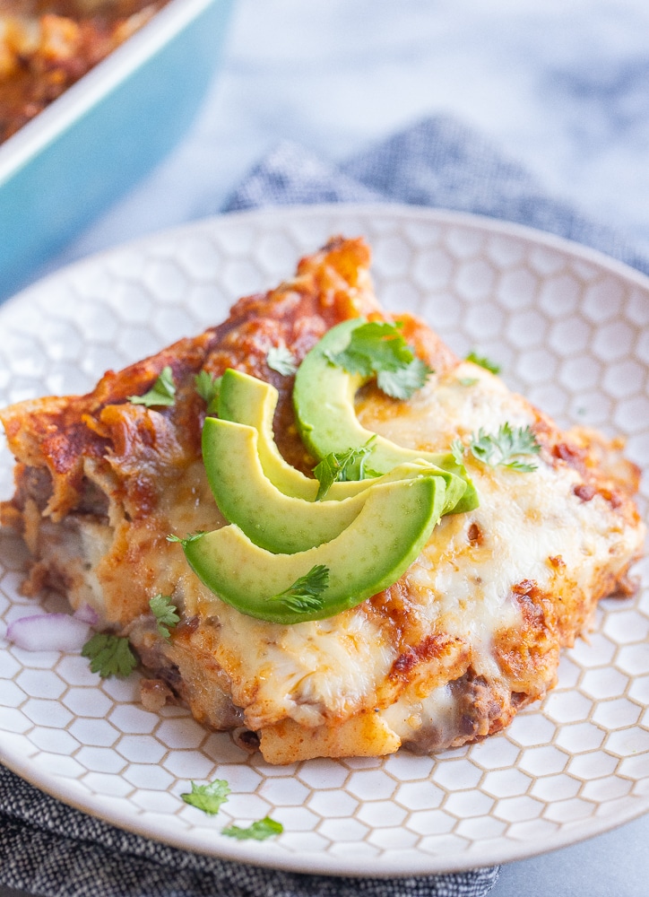 slice of cheese enchilada casserole served for dinner with avocado