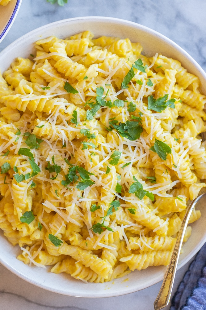 close up of a bowl of creamy golden squash pasta with parmesan and parsley