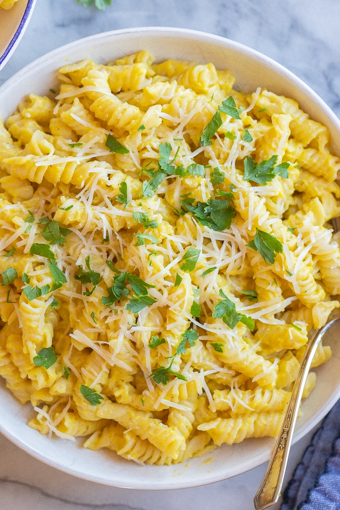 close up of a bowl of creamy golden squash pasta with parmesan and parsley