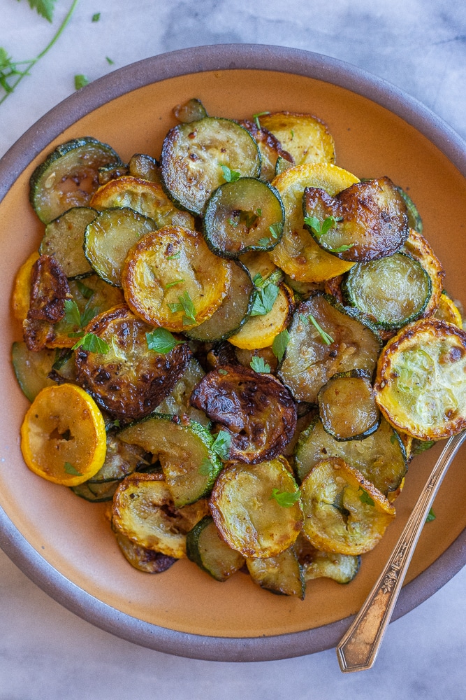 plate full of pan fried summer squash and zucchini topped with parsley