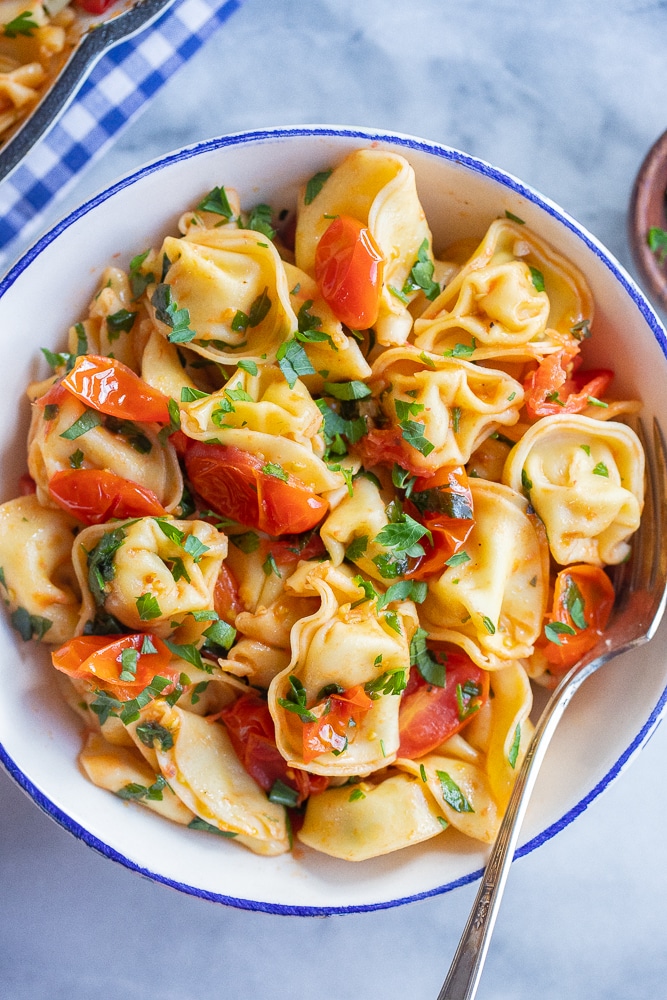 bowl of cheese tortellini with tomatoes and parsley
