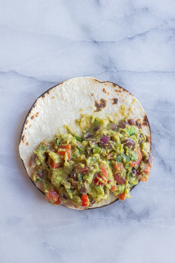 a loaded guacamole taco assembled on a cutting board