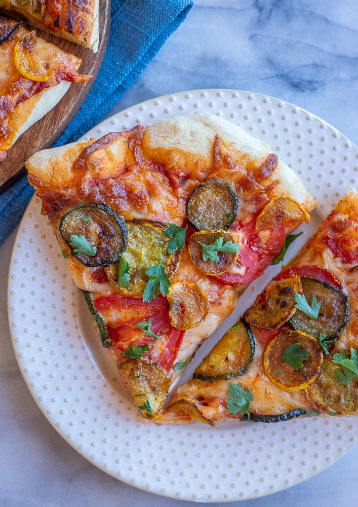 a slice of summer squash pizza with tomatoes and fresh herbs