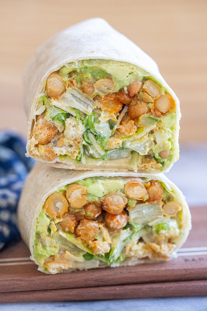 two chickpea Caesar salad wraps stacked on top of each other on a cutting board