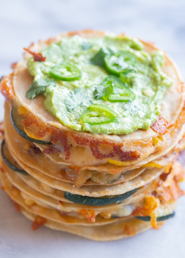 five corn and zucchini quesadillas stacked on top of each other with golden brown melted cheese