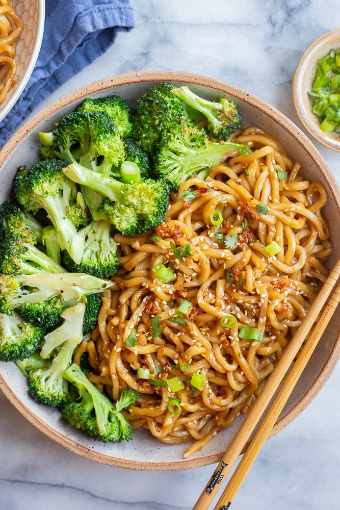 a large bowl of teriyaki stir fry noodles with broccoli and chopsticks