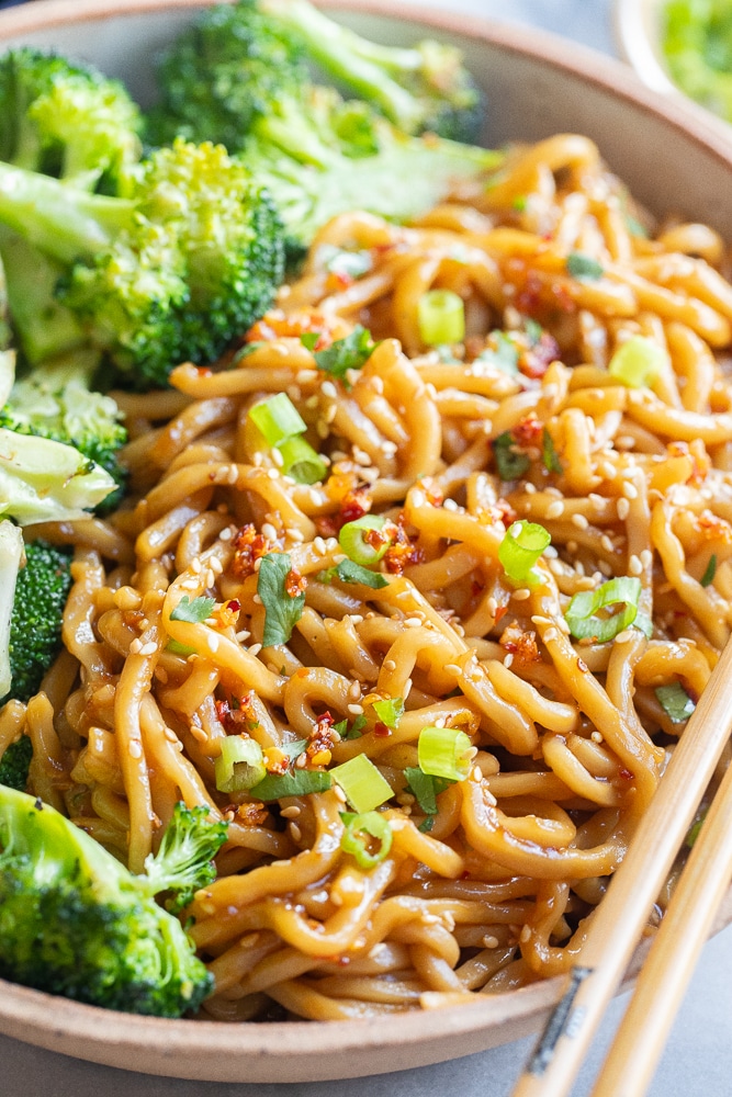 close up of saucy noodles in a bowl with toppings