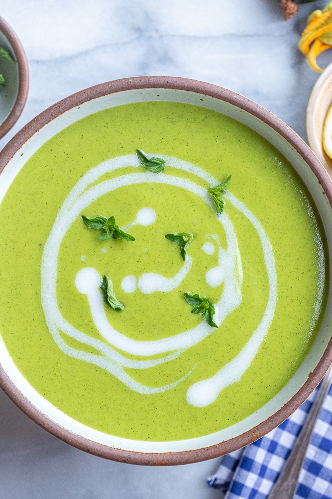bowl of curried zucchini soup with coconut milk and mint leaves