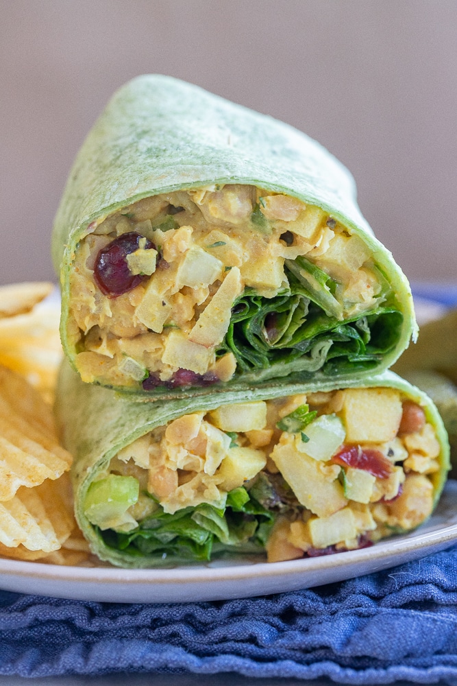 curried chickpea wrap cut in half on a plate with chips