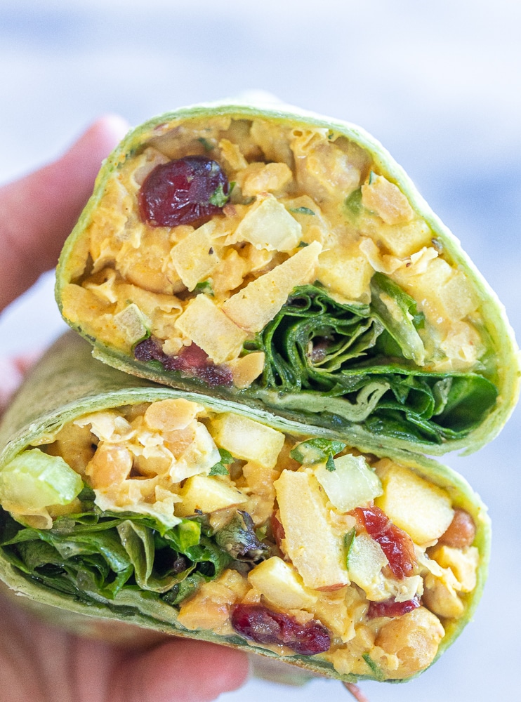 close up of a hand holding two chickpea curried salad wraps