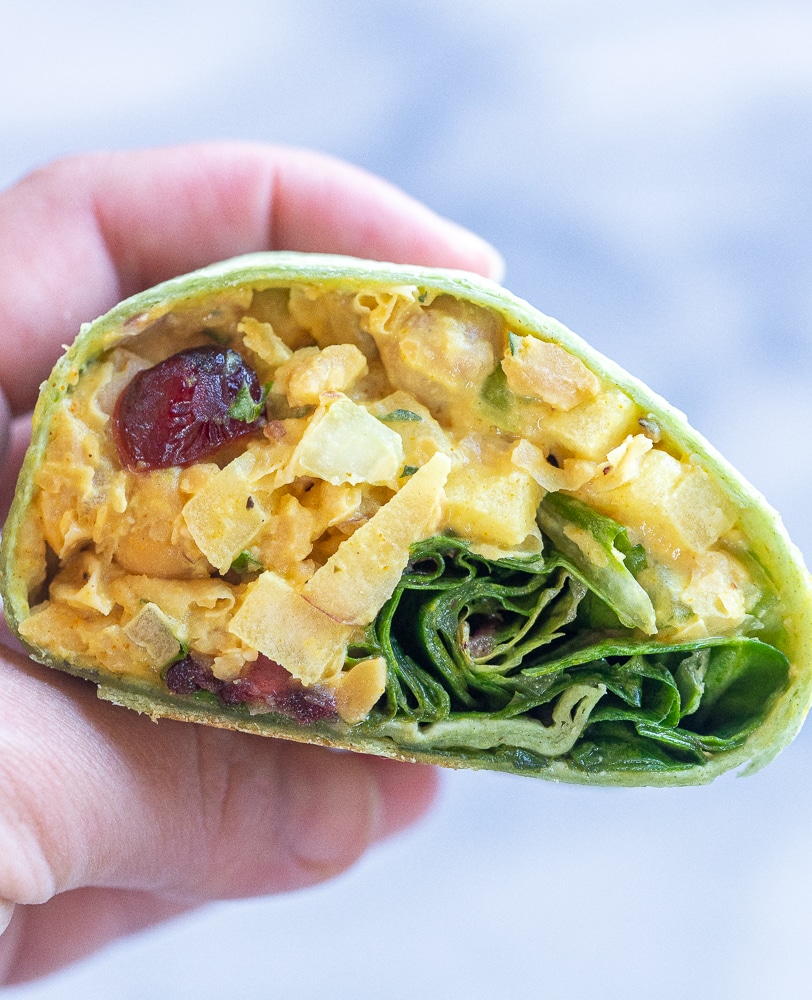 a hand holding half of a chickpea Salad wrap