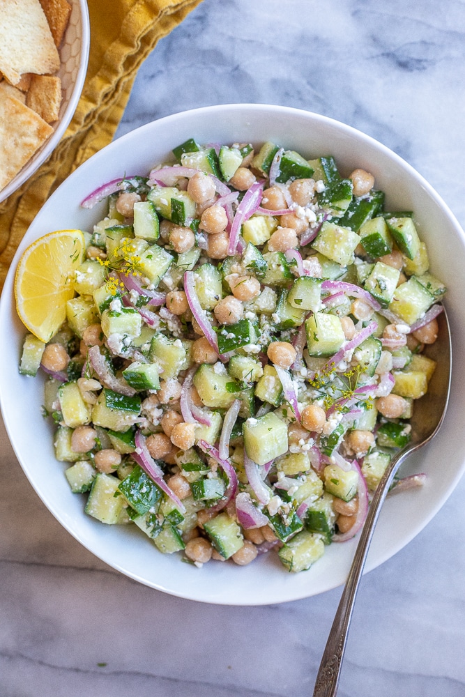 chickpea cucumber salad in a serving bowl with a lemon