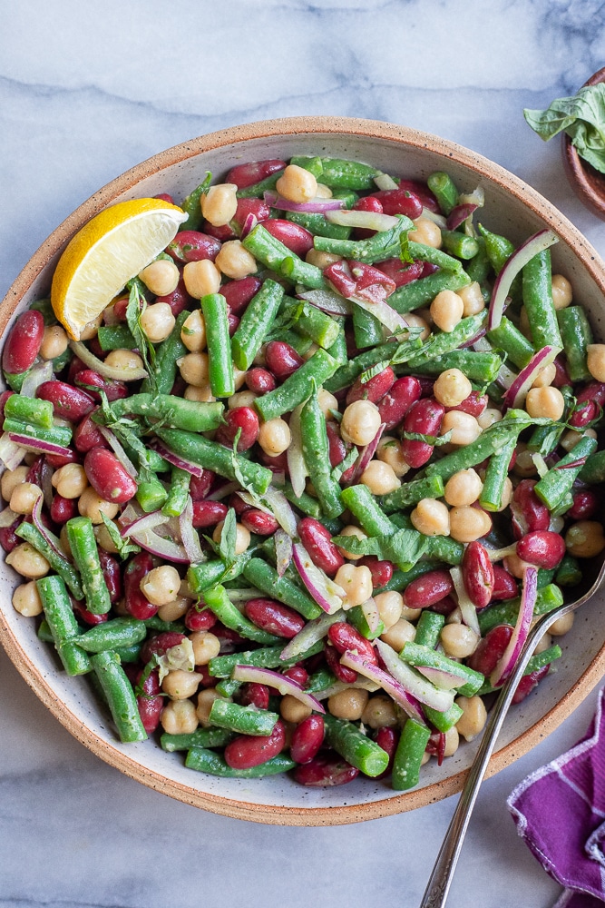 big bowl of three beans Salad with basil vinaigrette and a serving spoon