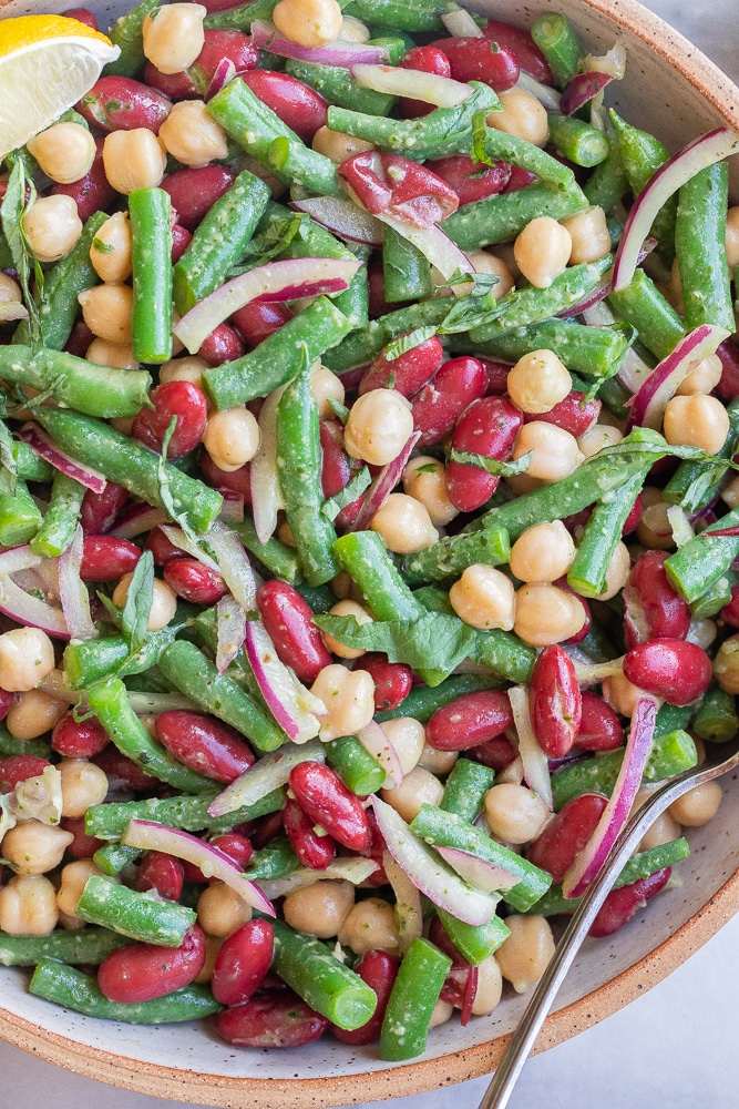 summery three bean salad in a serving bowl with basil vinaigrette