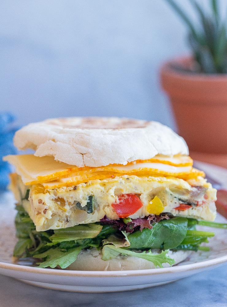frittata breakfast sandwich on a plate with cheese and salad
