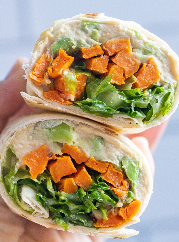 roasted sweet potato wraps with honey mustard cut in half being held by a hand