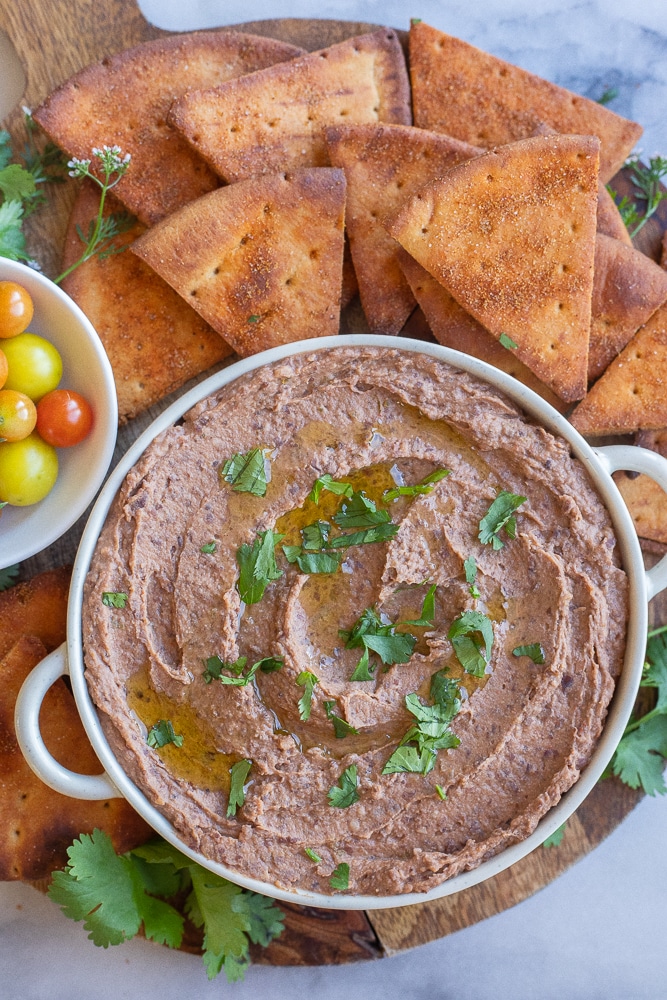 black bean hummus in a bowl with pita chips and tomatoes