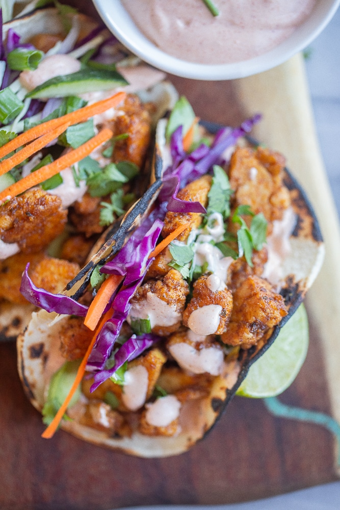 close up of a blackened tofu taco topped with fish taco sauce