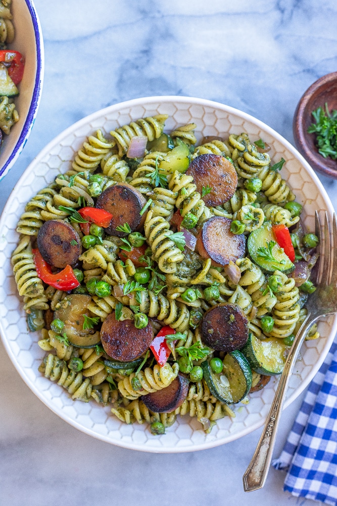a big bowl of crispy sausage pesto pasta with vegetables