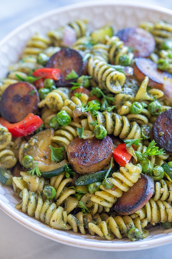close up of crispy sausage pesto pasta with vegetables