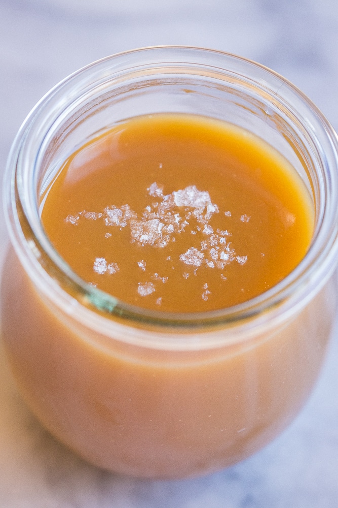 close up of tahini caramel sauce in a jar with sea salt