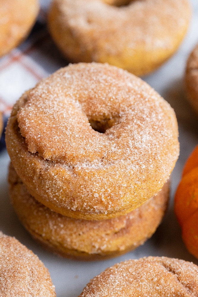 two baked pumpkin donuts stacked on top of each other with cinnamon sugar