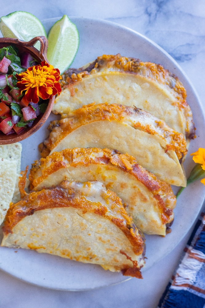 a plate with four pumpkin and black bean tacos and a side of salsa