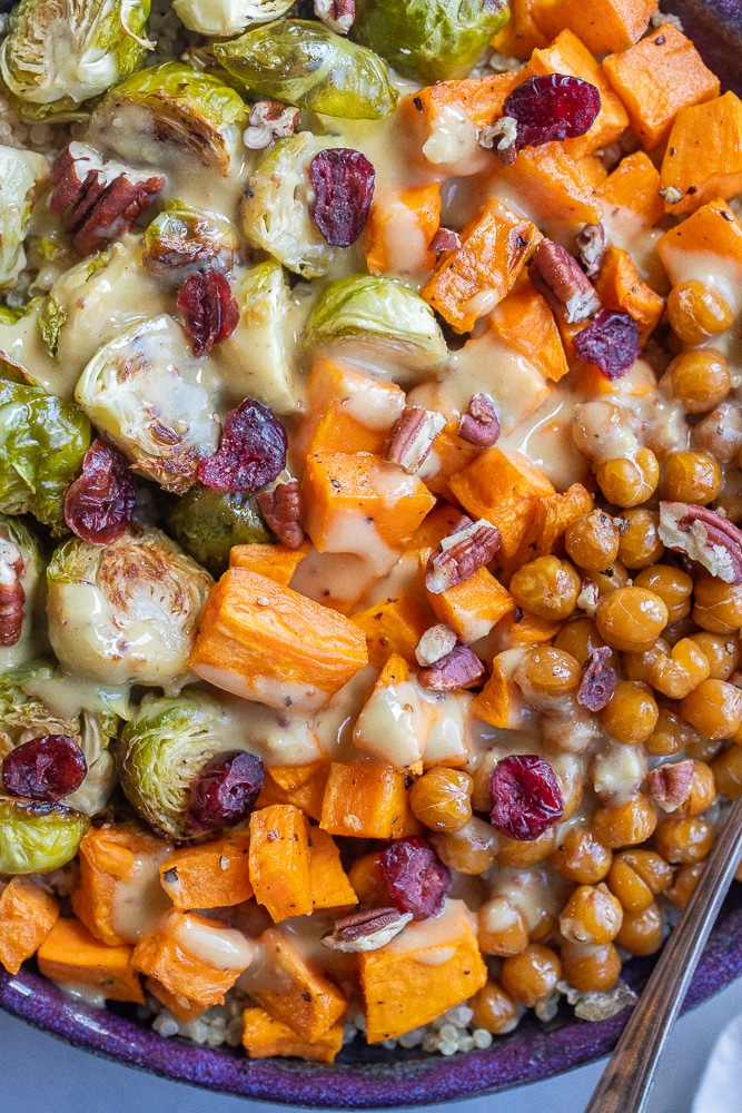 close up of roasted veggie bowl topped with creamy tahini honey mustard dressing