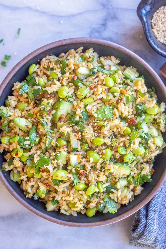 cucumber edamame rice salad in a serving bowl with toasted sesame seeds