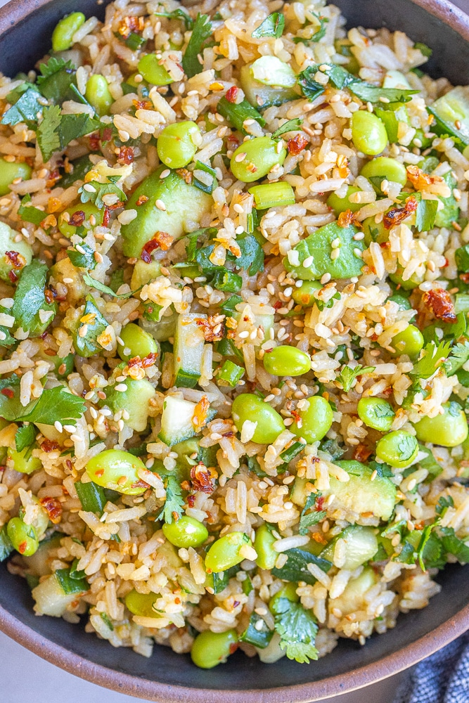 close up of a bowl of cucumber edamame rice salad with avocado