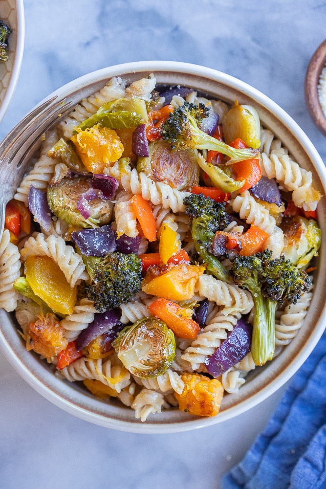 roasted vegetable pasta with parmesan cheese in a bowl with a fork