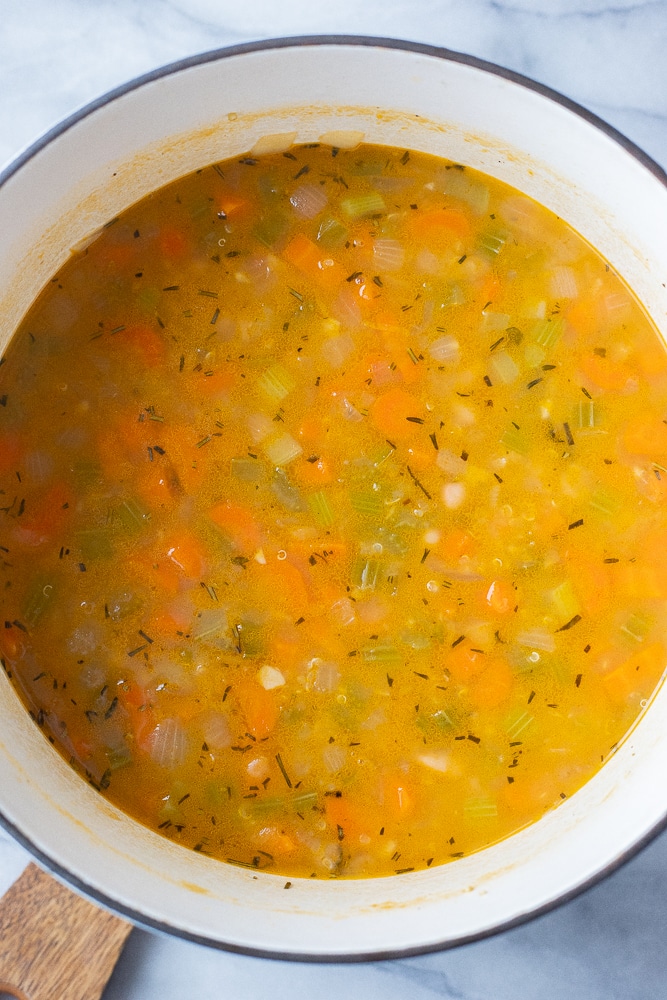 lemony white bean soup in a soup pot with fresh herbs