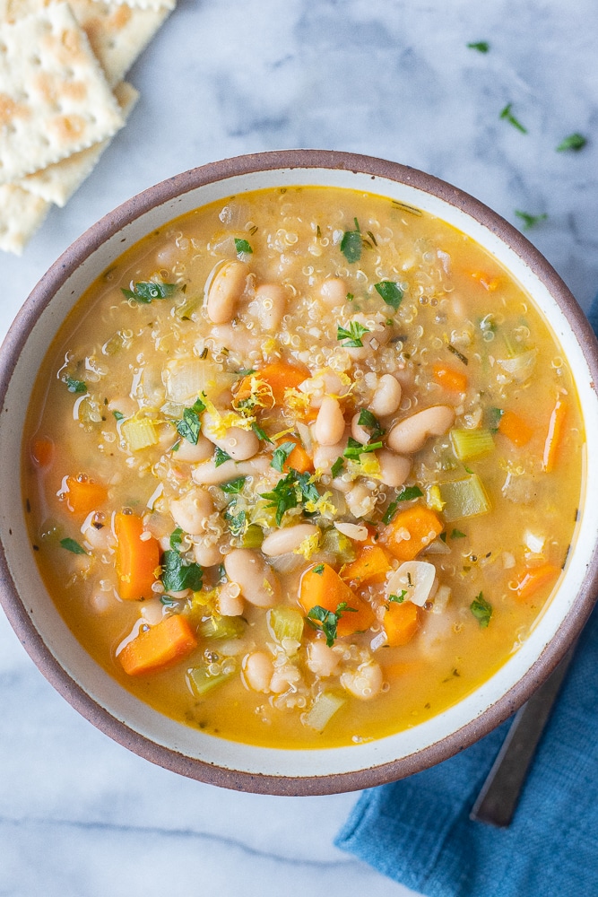 bowl of lemony white bean soup with quinoa in a bowl with saltine crackers