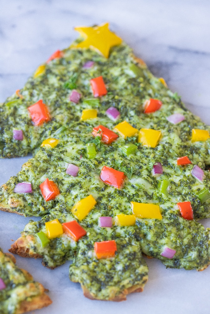 close up of a naan pesto pizza topped with peppers and onions