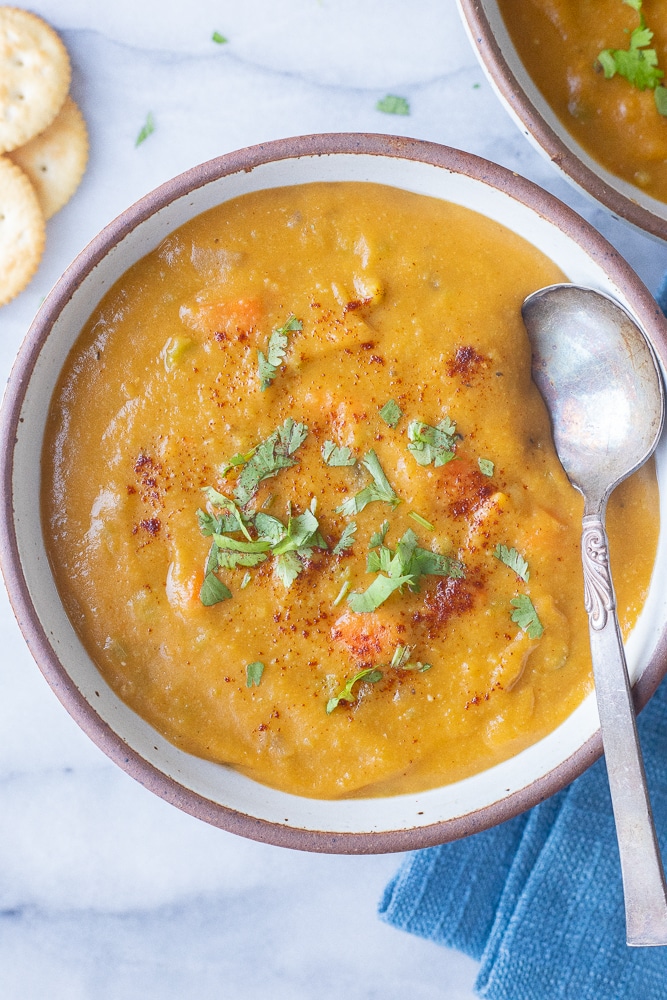 bowl of smoky vegetarian split pea soup with a spoon and crackers