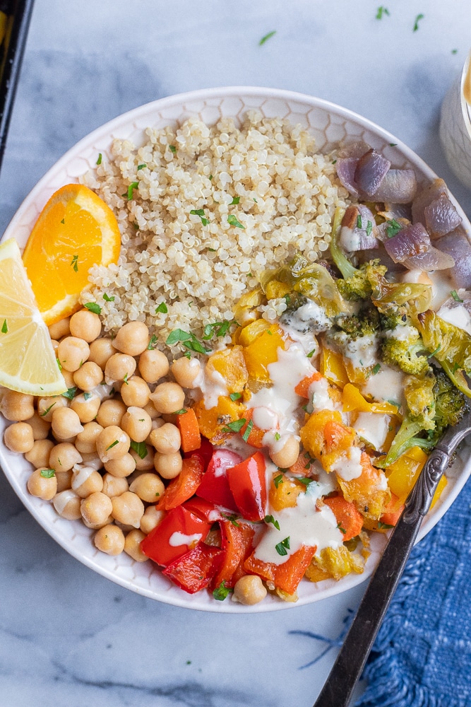 roasted rainbow veggie bowls with citrus tahini sauce with a fork and napkin