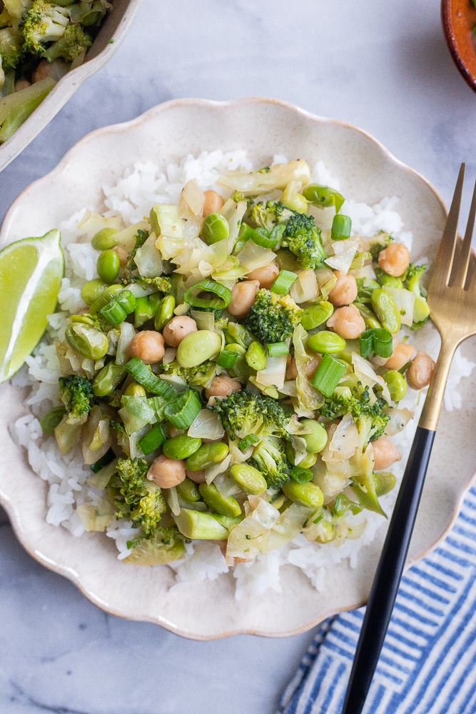 green veggie rice bowls on a plate with a fork and lime wedge