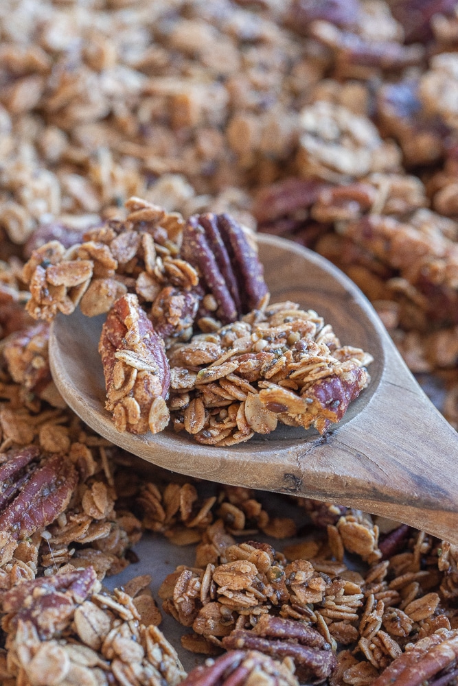 large wooden spoon full of clusters of maple pecan granola