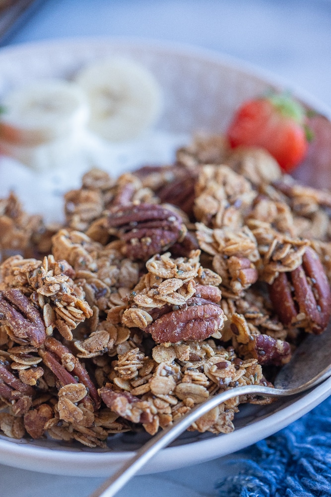 Bowl of homemade chunky maple pecan granola with yogurt and fruit